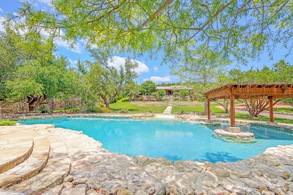 Soak up the Texas sun in your own private oasis—natural stone pool, shaded pergola, and lush greenery create the perfect Hill Country escape
