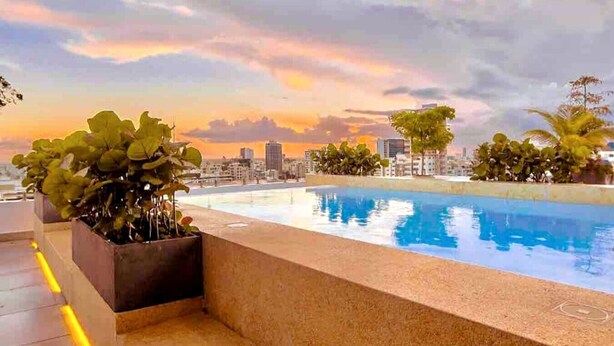 A rooftop pool with a cityscape view at sunset.