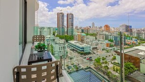 A balcony with a view of a cityscape, including high-rise buildings and a clear sky.