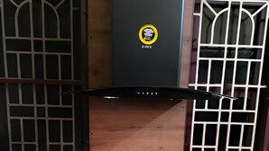 Une cuisine dotée d’une hotte centrale, de deux meubles de rangement latéraux et d’un plan de travail en bois.