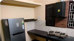 Une cuisine équipée d’un réfrigérateur, d’une cuisinière et d’une fenêtre avec un grillage.