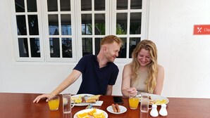 Una mesa de desayuno con fruta, salchichas y una jarra de jugo.