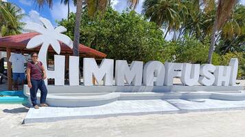 Une grande enseigne blanche sur laquelle on peut lire le mot « HIMMAFUSH », avec des palmiers en arrière-plan.