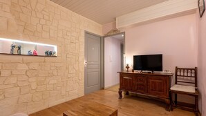 Ein Wohnzimmer mit Steinwand, Holzmöbeln, einem Fernseher und einem Schrank.