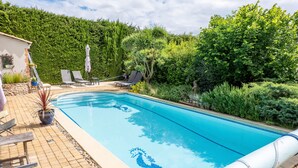 Ein Swimmingpool mit einem Seepferdchen-Design, umgeben von Liegestühlen und Topfpflanzen.