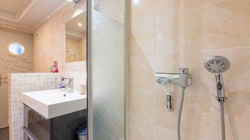A modern bathroom with a glass shower enclosure, a white sink, and a handheld showerhead.