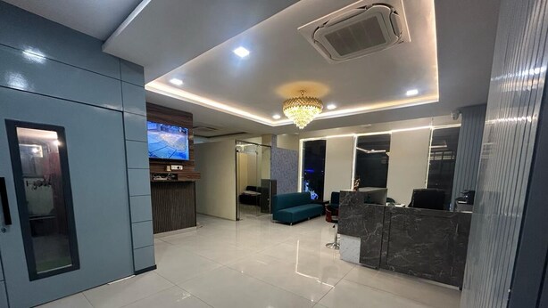 Una hall d'albergo moderna con reception, area salotto e lampadario.