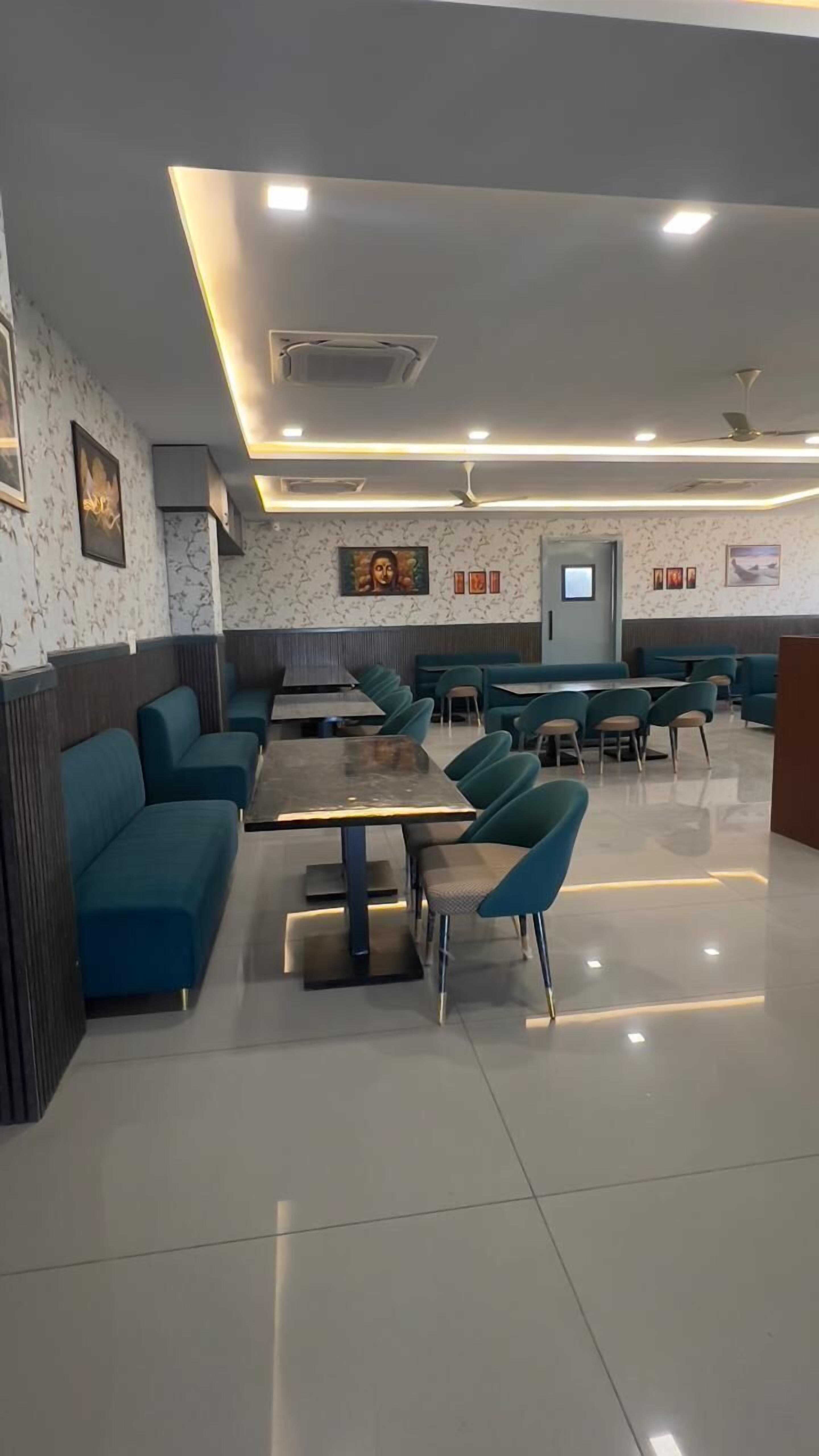 A modern restaurant with teal seating, a central dining area, and a ceiling with recessed lighting.