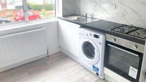 A compact kitchen with a built-in washer, oven, and a window overlooking a street.
