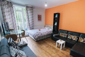 A modern living room with a bed, a sofa, a small table, and a bookshelf. - Big Apartment in Paddington - Central London - Families :) (London)