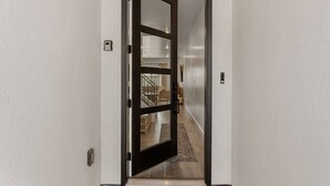 A hallway with a wooden door leading to a room with a staircase. - Adventure Basecamp: Hot Tub + Resort Amenities (Washington)