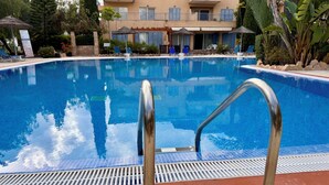 A swimming pool with metal railings, a blue sign with '1.80M' indicating the depth, and a building with balconies and plants in the background. - RelaxInCyprus 1-bedroom apartment in awesome Pegeia with WiFi, AC (Pegeia)