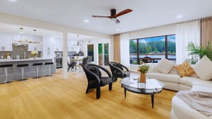 Una sala de estar moderna con un sofá, dos sillones, una mesa de centro y vista a un lago a través de amplios ventanales.