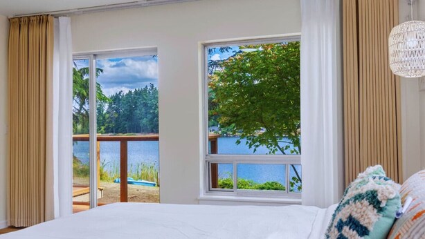 Un dormitorio con una cama grande, vistas a un lago y un balcón con barandilla de madera.