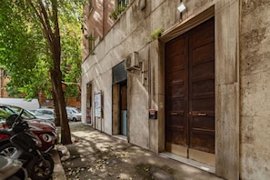 Un bâtiment doté de grandes portes de garage en bois, d’un arbre et de motos garées.