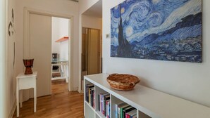 A hallway with a painting, a bookshelf, and a basket. - GuestHost - Cozy apartment of about 70 sqm, able to accommodate up to 4 people, located on the fourth floor of a building with a lift (NOT suitable for disabled people).The property is located in the Flaminio district, close to the Lungotevere, in a well (Rome)