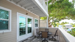 A covered patio with a table and chairs, a sliding glass door, and a view of the surrounding area. - Casa Bonita Key West ~ by Rent Key West Vacations (Key West)