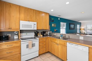 A modern kitchen with wooden cabinets, a microwave, stove, and dishwasher. - Casa Bonita Key West ~ by Rent Key West Vacations (Key West)