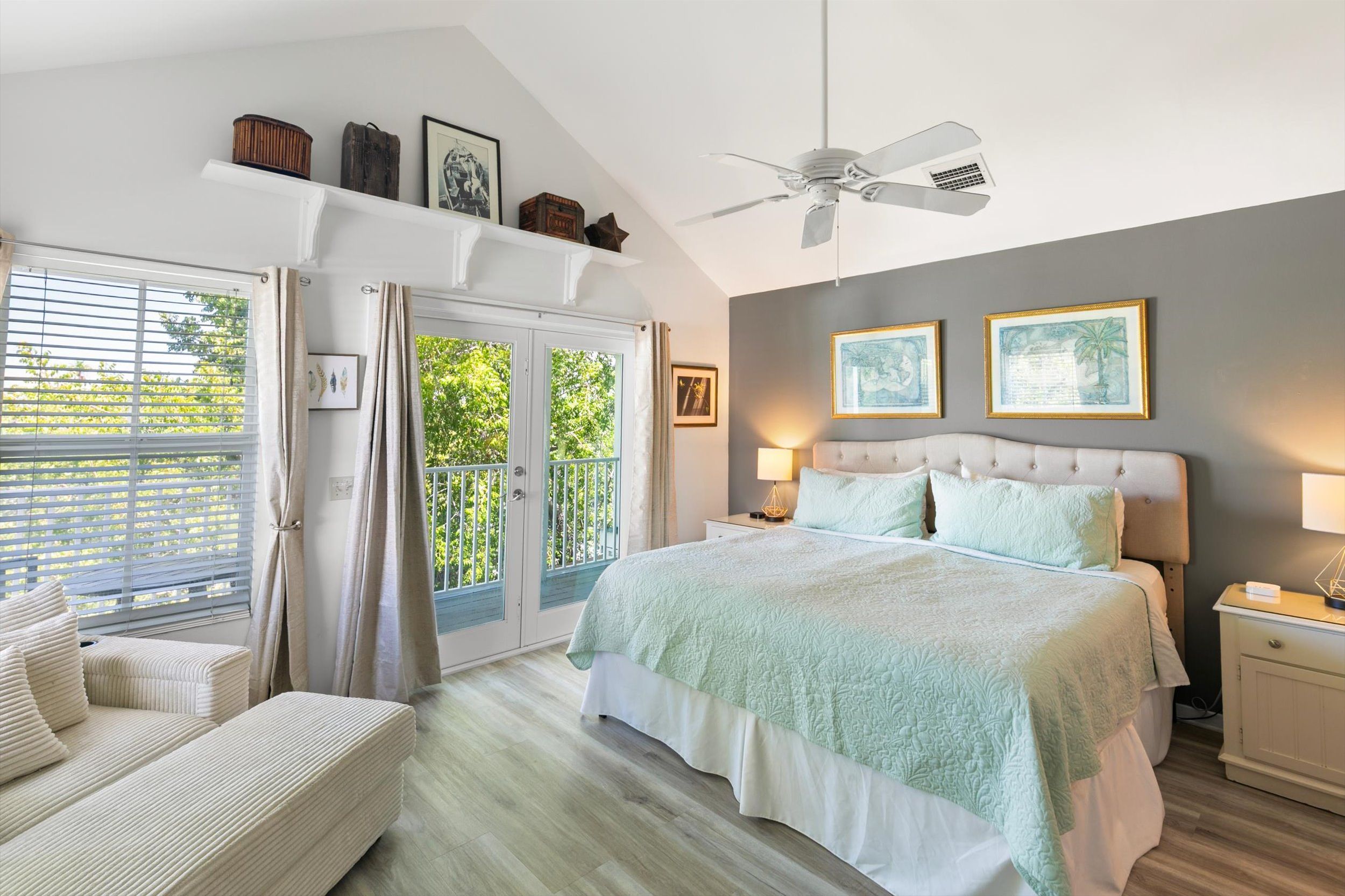 A bedroom with a bed, a nightstand, a chair, a ceiling fan, and a window with curtains.