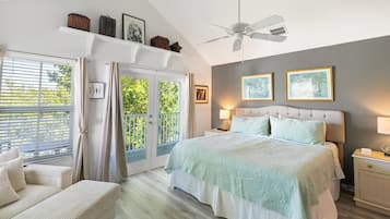 Quarto com cama, mesa de cabeceira, cadeira, ventilador de teto e janela com cortinas.