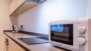 Une cuisine moderne dotée d’un four à micro-ondes encastré, d’une machine à café et d’un plan de travail élégant.