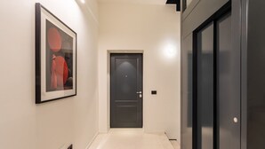Un couloir avec une œuvre d’art encadrée au mur, une porte et un ascenseur noir.