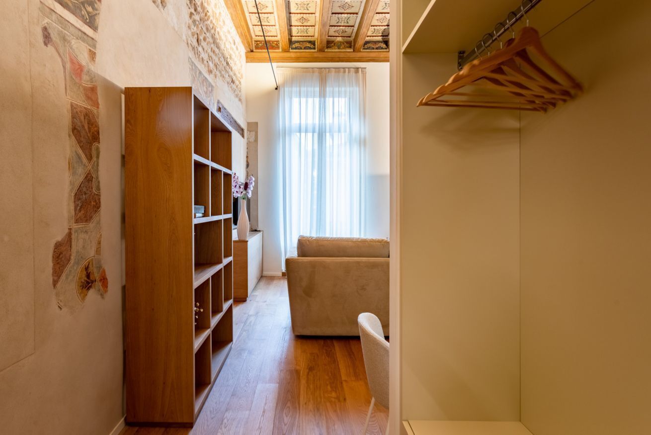 Un couloir avec une armoire en bois, un canapé beige et un portant à vêtements.