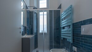 A modern bathroom with a glass shower enclosure, a bathtub, and a vanity with a towel rack. - Studio apartment with double bed, armchair bed and equipped kitchenette. (Turin)