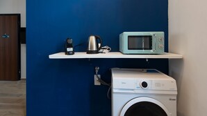 A laundry area with a washing machine, a kettle, and a microwave on a shelf. - Studio apartment with double bed, armchair bed and equipped kitchenette. (Turin)