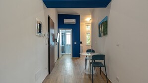 A narrow hallway with a blue ceiling, a round table with chairs, and a door leading to a room. - Studio apartment with double bed, armchair bed and equipped kitchenette. (Turin)