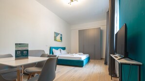 A modern hotel room with a bed, a desk, a chair, a television, and a table. - Superior Studio | Hotiday Torino OGR (Turin)