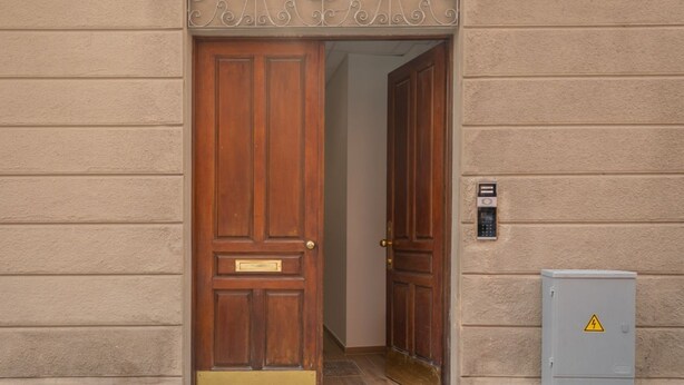 A wooden door with a brass plate, a keypad, and a warning sign on a utility box. - Superior Studio | Hotiday Torino OGR (Turin)