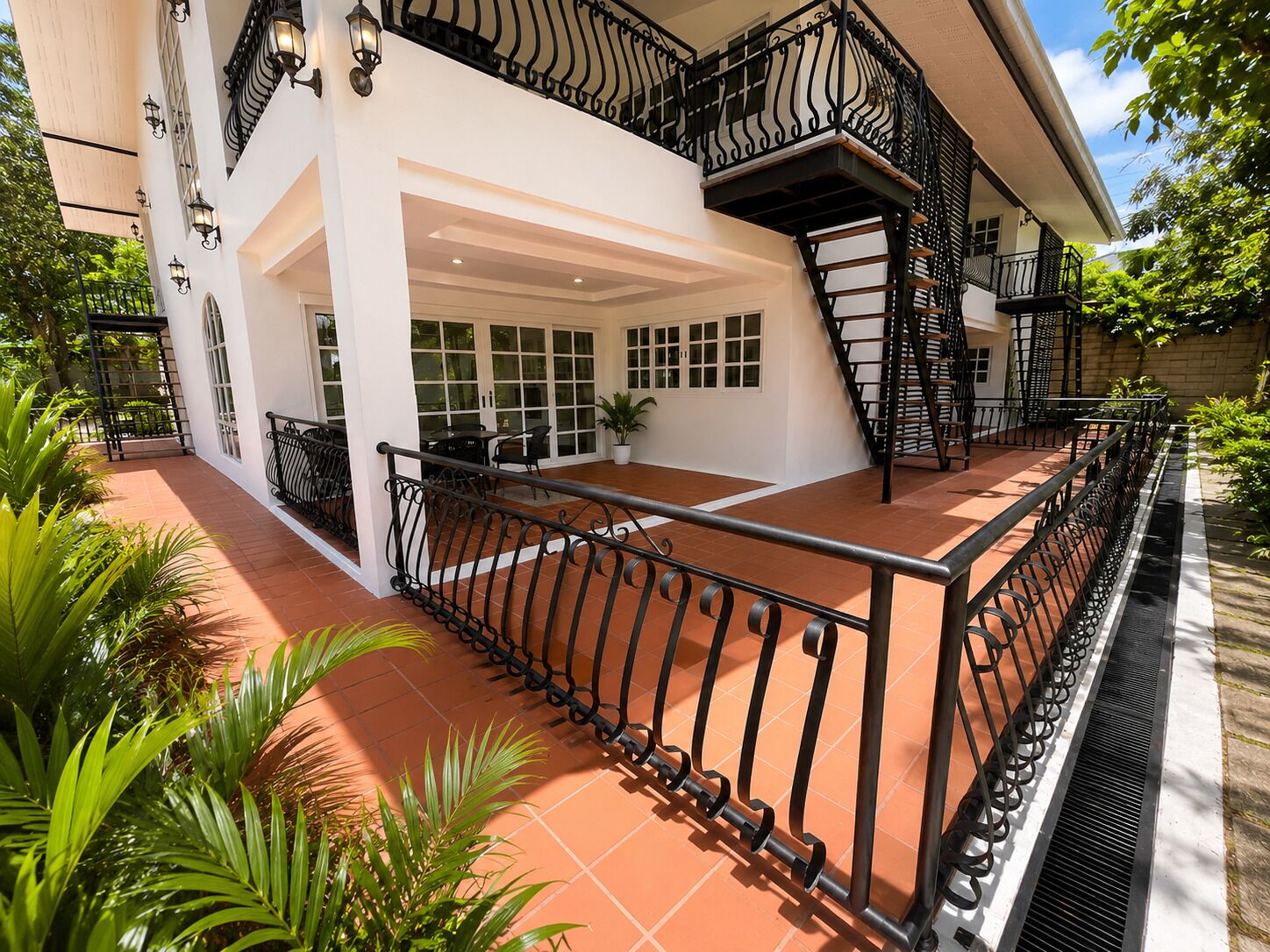 A multi-story building with a balcony, a staircase, and a covered patio area.