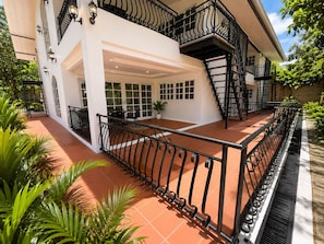 Un edificio de varios pisos con un balcón, una escalera y un patio cubierto.