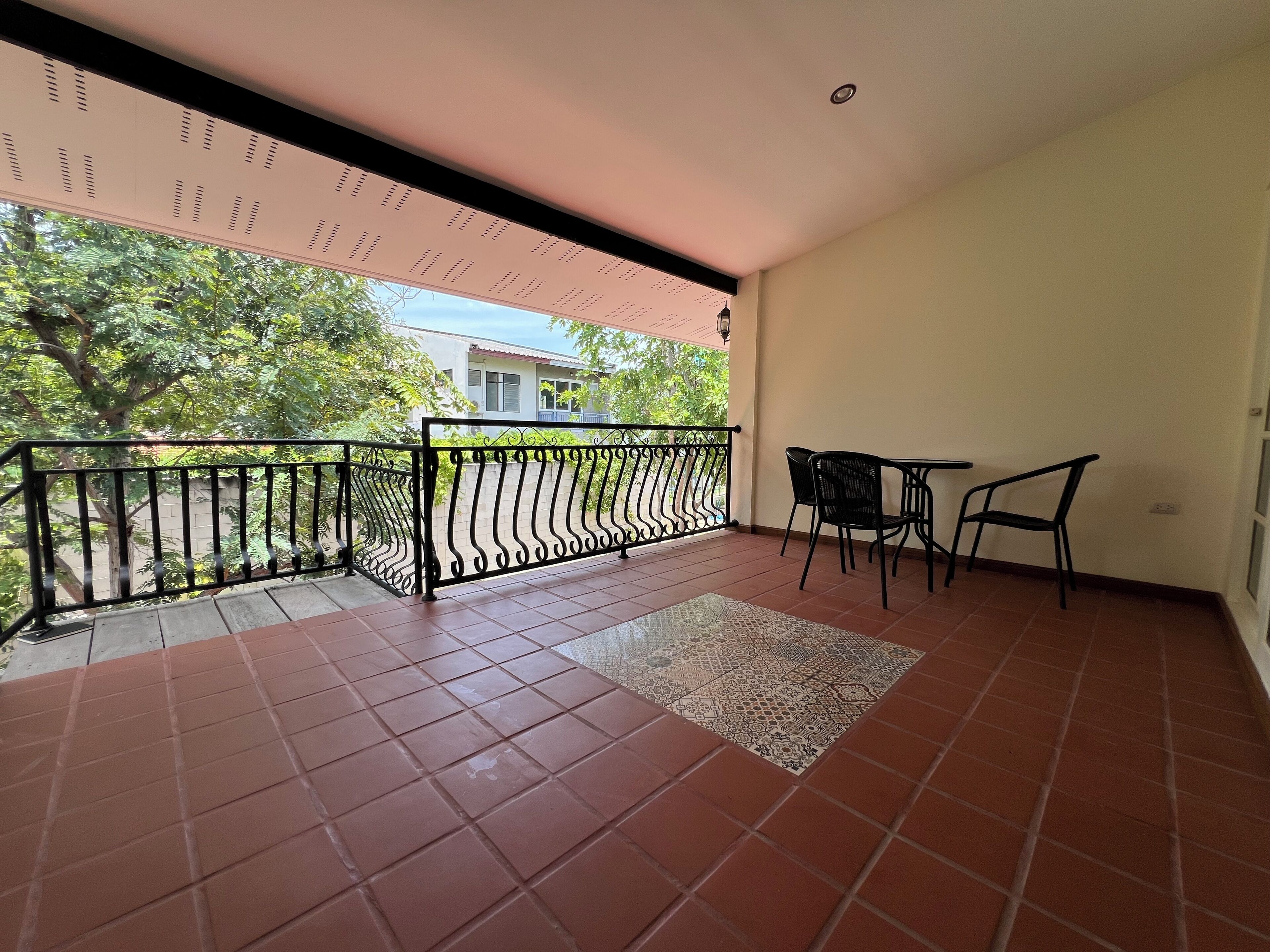 A balcony with a tiled floor, a metal railing, and two chairs.