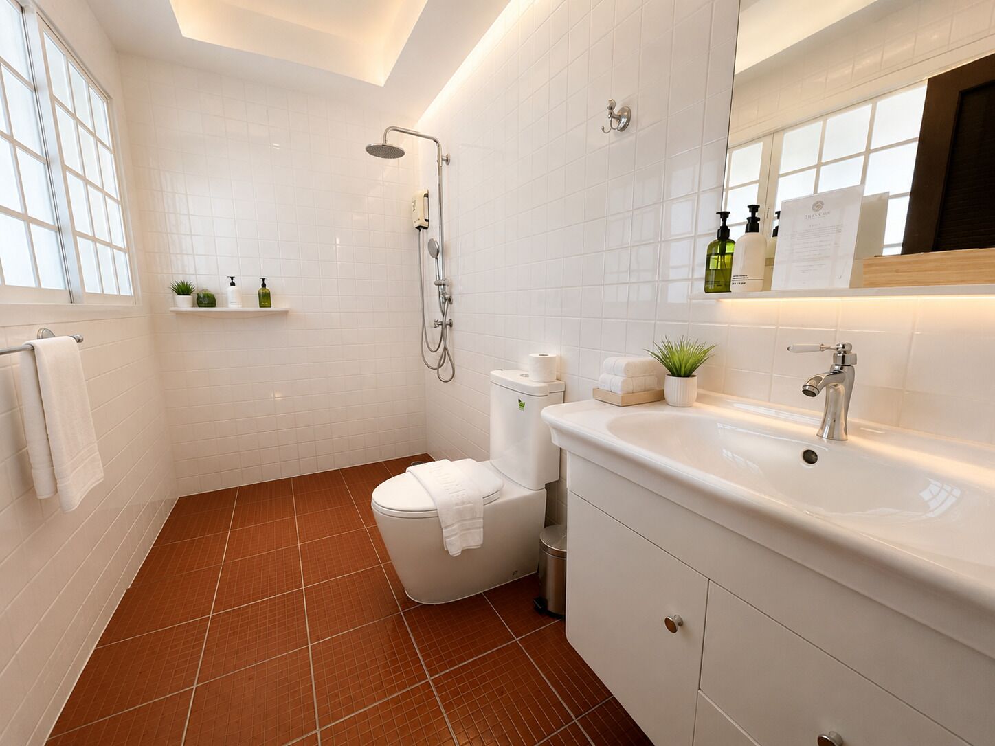 Un baño moderno con ducha, inodoro, lavamanos y espejo sobre el lavamanos.