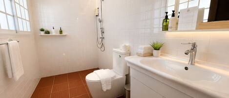 Un baño moderno con ducha, inodoro, lavamanos y espejo sobre el lavamanos.