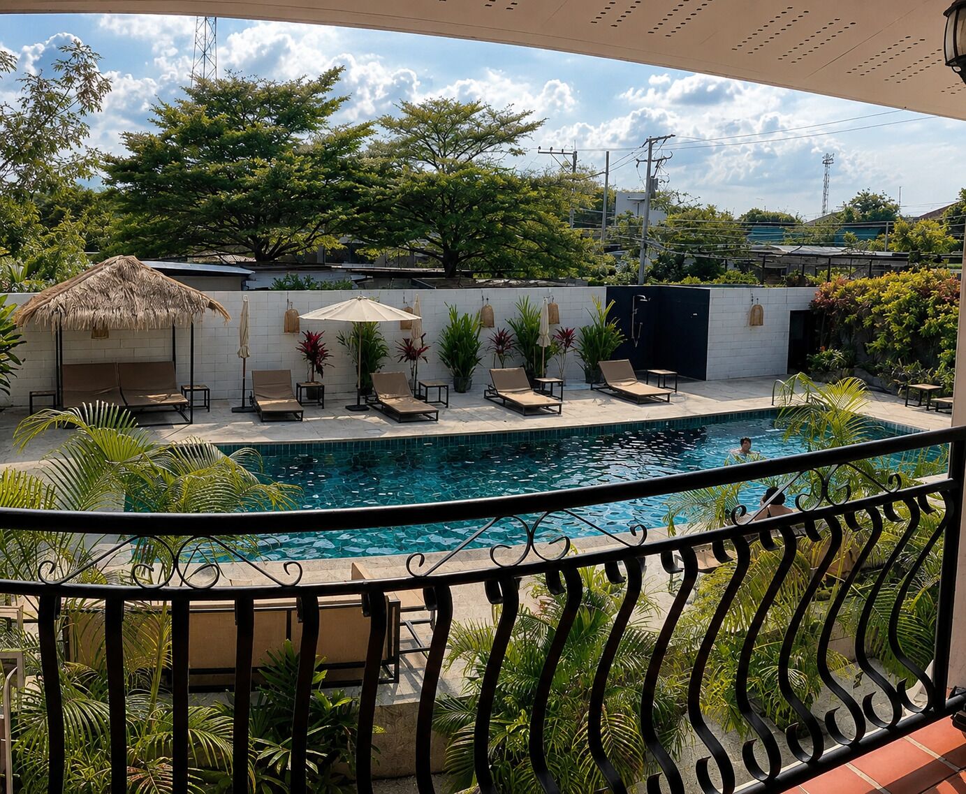 Un espace aménagé au bord de la piscine, avec des chaises longues, des parasols et une structure recouverte de chaume.