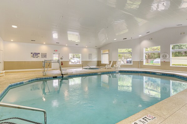An indoor swimming pool with clear water, a lifeguard station, and windows providing natural light.
