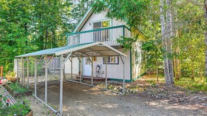 A two-story wooden cabin with a covered porch and a fenced garden area. - 2 Mi to Lake Cushman Access: PNW Cabin Retreat! (Hoodsport)