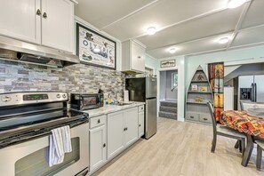 Une cuisine moderne avec des meubles blancs, un réfrigérateur en acier inoxydable, un four à micro-ondes et une cuisinière.