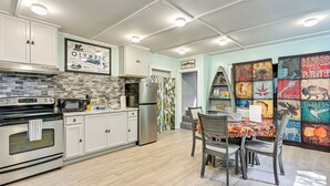 A modern kitchen with white cabinets, a stainless steel refrigerator, and a dining area with a colorful tablecloth. - 2 Mi to Lake Cushman Access: PNW Cabin Retreat! (Hoodsport)