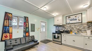 A modern kitchen with white cabinets, a black stove, and a tiled backsplash. - 2 Mi to Lake Cushman Access: PNW Cabin Retreat! (Hoodsport)