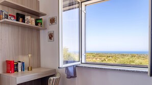 Une pièce avec une fenêtre, une bibliothèque, une lampe, une chaise et une vue sur le paysage.