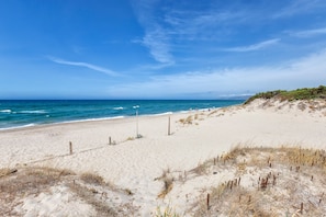 Een strand met zand, een hek en de oceaan.