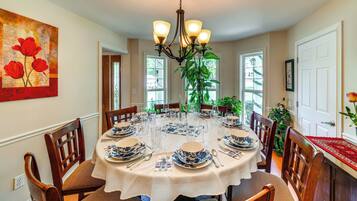 A dining room with a round table set for six, surrounded by wooden chairs.