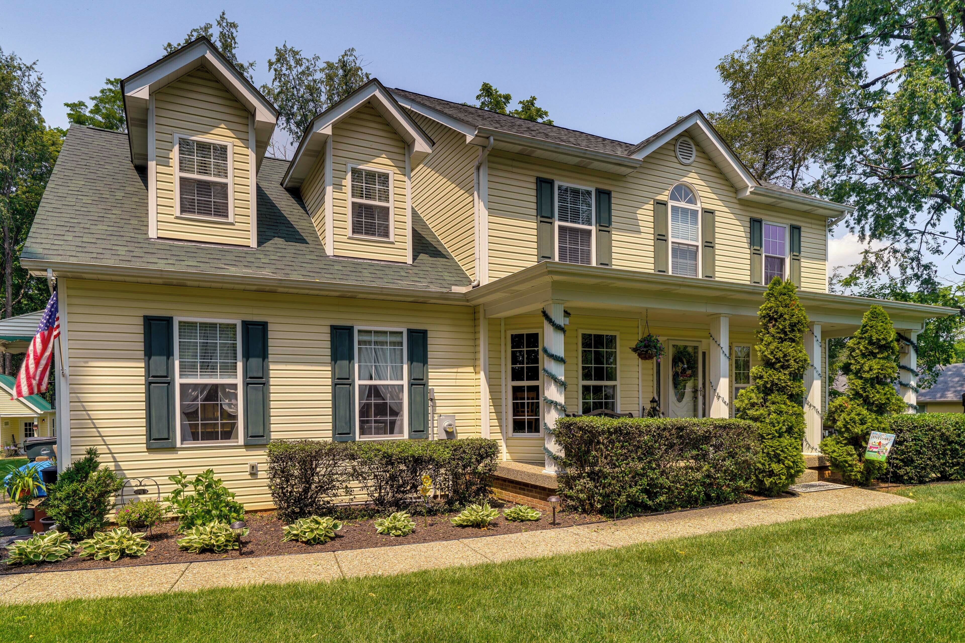 A two-story house with a front porch, a small garden, and a flag.