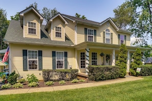 A two-story house with a front porch, a small garden, and a flag. - 15 Mi to Louisville: Family Home w/ Private Yard! (Louisville)