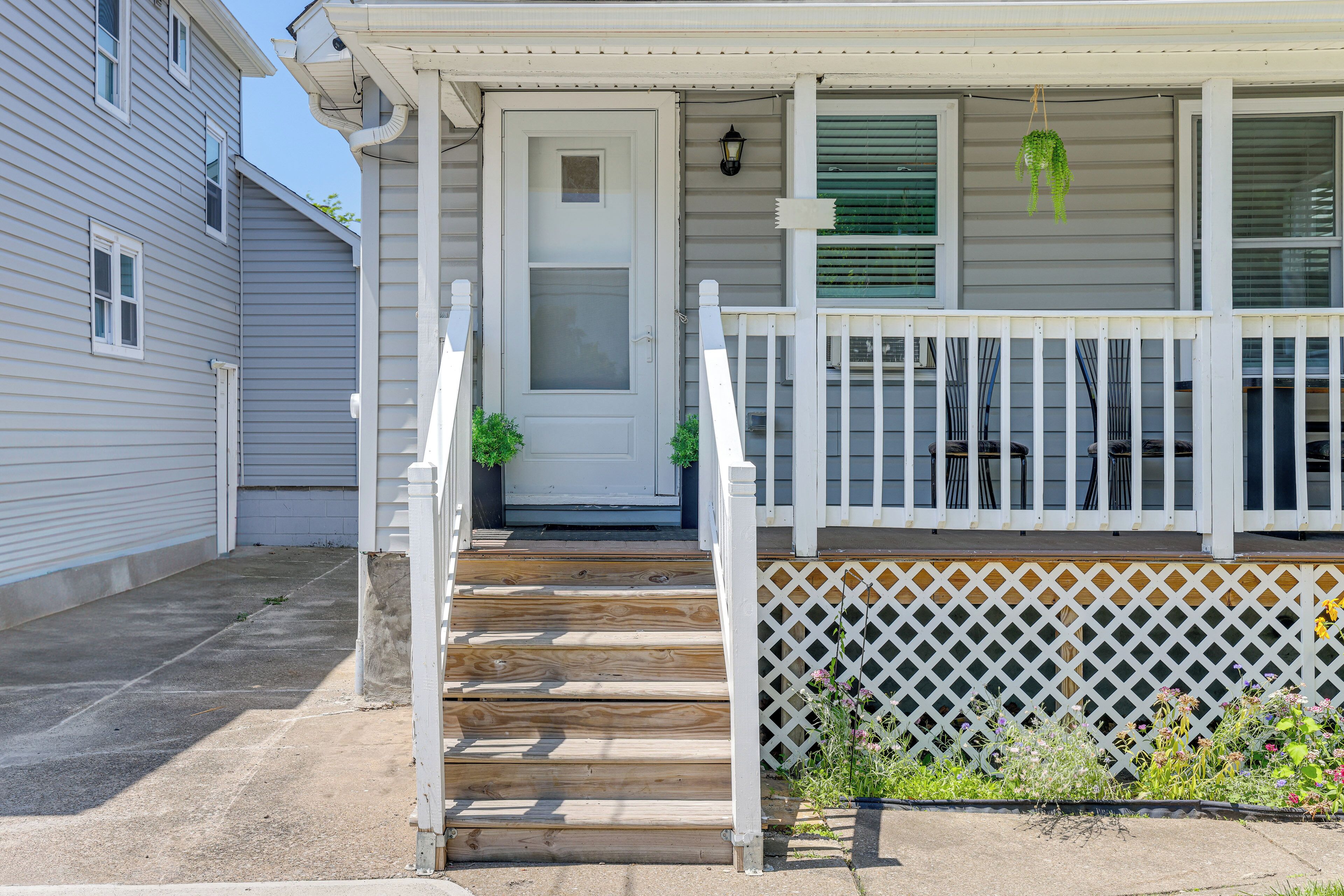 A front porch with wooden steps, a white door, and a white picket fence.