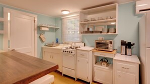 A compact kitchen with white cabinetry, a wooden dining table, a gas stove, a built-in oven, and a microwave. - Fish & Hike: Lakeside Poconos Retreat, Unit 4 (Bangor)